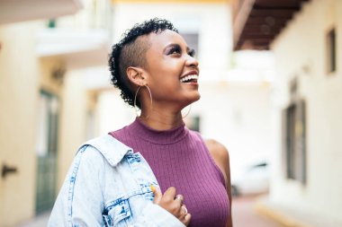 Kısa kıvırcık saçlı ve büyük küpeli havalı bir Afro-Amerikan kadının portresi