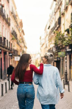 Sokakta yürüyen iki genç kızın arka görüntüsü.