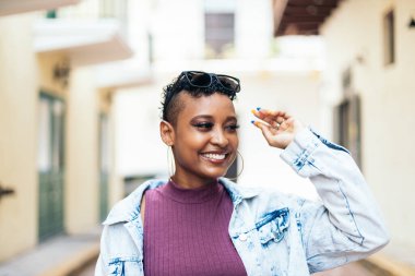 Kısa kıvırcık saçlı ve büyük küpeli havalı bir Afro-Amerikan kadının portresi