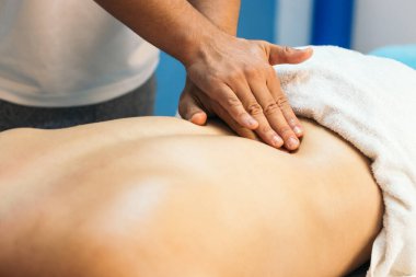 Klinikte bir hastayı tedavi eden bir kayropraktik uzmanının yakın çekimi. Fizyoterapist hastanın sırtına masaj yapıyor. 