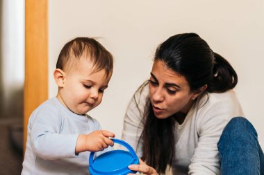 Anne, bebeğiyle evde oynuyor.