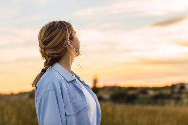 Sahada gün batımına bakan genç sarışın kadın