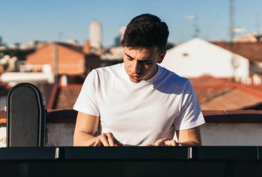 Çatıda klavye çalan bir adamın ön görüntüsü.