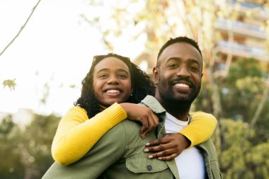 Gülümseyen siyah bir adamın portresi kız kardeşine sırtına bindirirken