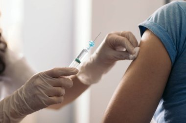 Doktor aşıdan önce pamukla kol temizliği yapıyor.