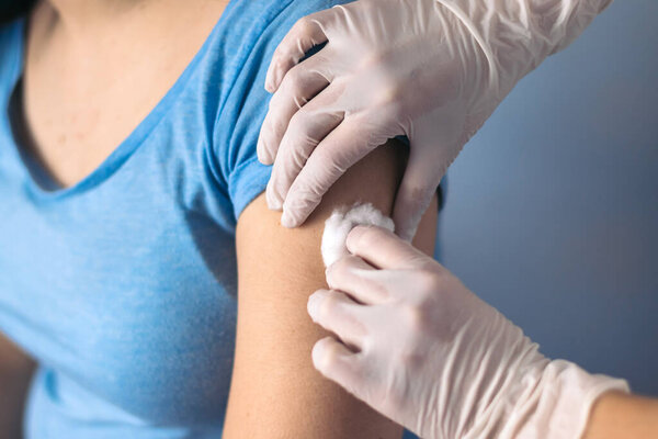 Doctor cleaning arm to give a vaccine to a patient
