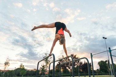 Kadın sporcu paralel barlarda amuda kalkıyor.