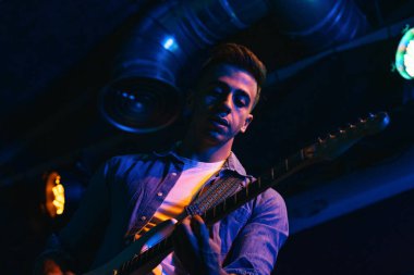 Hit the Note: Müzik grubu canlı konser sırasında kapalı bir sahnede renkli ışıklandırmayla şarkı söylüyor ve enstrümanlar çalıyor