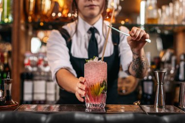 Kadın barmenin kokteyl doldurup garnitürle süslediği yakın plan.