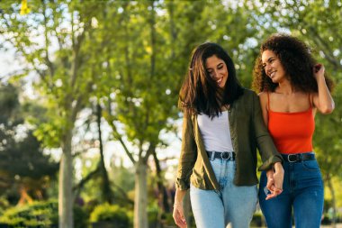 Parkta el ele tutuşan iki genç kadın..