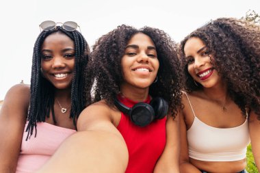 Afro saçlı üç Afrikalı Amerikalı kızın gülüşü. Mutlu anları yakalamak için fotoğraf çekiyorlar.