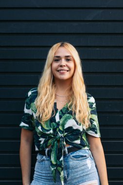 Açık havada gülümseyen sarışın bir kızın portresi.