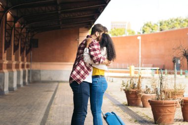 Çok ırklı genç bir çift istasyonda buluştuktan sonra sarılıp öpüşüyorlar. Yolculuğundan kalma mavi bir bavul taşıyor ve adam gülümsemesini bekliyor. Birbirlerini tekrar gördükleri için mutlular.