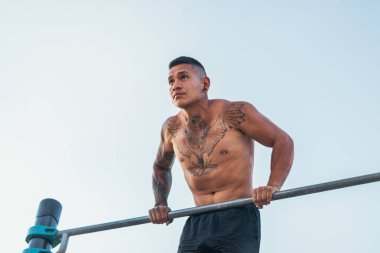 Erkek sporcu açık havada bir barda dalış yapıyor.