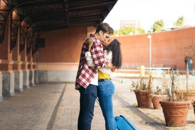 Çok ırklı genç bir çift istasyonda buluştuktan sonra sarılıp öpüşüyorlar. Yolculuğundan kalma mavi bir bavul taşıyor ve adam gülümsemesini bekliyor. Birbirlerini tekrar gördükleri için mutlular.