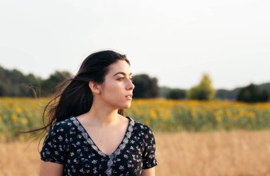 Tarlada kısa bir yaz elbisesi giyen uzun saçlı güzel bir genç kadın. Gülümsüyor ve İspanya 'da yazın tadını çıkarıyor.