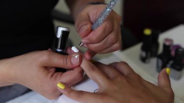 Gündüz vakti güzellik salonunda kadın müşterilere manikür yapan tanınmamış bir manikürcü.
