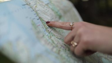 Kırsaldaki çayırlarda kağıt haritalı, yüzüklü, tanınmayan bir kadın gezgin eli.