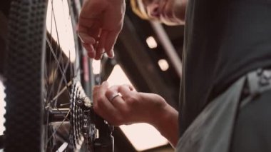 Aşağıdaki tanınmayan erkek üstat tamir atölyesinde çalışırken İngiliz anahtarıyla bisiklet tekerleklerini düzeltiyor.