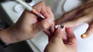 Gündüz vakti güzellik salonunda kadın müşterilere manikür yapan tanınmamış bir manikürcü.