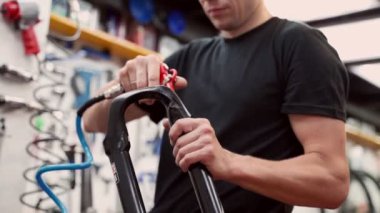 Tamir atölyesinde metal bisiklet çatalını temizlerken sıkıştırılmış hava tabancası kullanan tanınmamış bir erkek usta.