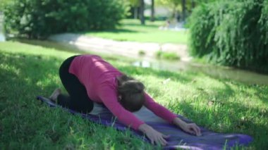 Çimenlikteki pilates eğitimi sırasında Utthita Balasana ve Bhujangasana pozisyonu üzerinde spor giyinen gerçek zamanlı kadın vücudu.