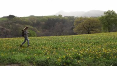 Dağlara karşı otlakta gezinirken cep telefonunda GPS uygulaması kullanan kadın yürüyüşçünün yan görüntüsü
