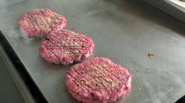 Fast food restoranının mutfağında pişen çiğ hamburger pirzolası.