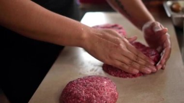 Lokanta mutfağında yemek pişirirken hamburgerler için taze etten pirzola hazırlayan isimsiz bir aşçı.