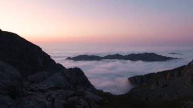 İspanya 'nın Asturias şehrinde gün batımında bulutlu gökyüzünün altında sisli deniz manzarası