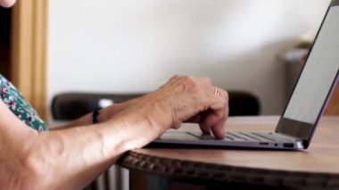 Tanımlanamayan yaşlı kadın elleri portatif bilgisayarda sörf yapıyor. Evde boş bir ekranla.