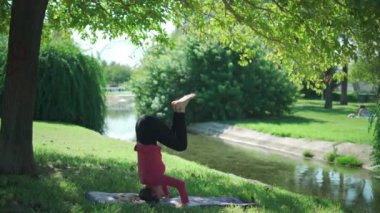 Ağaç ve derenin yanındaki parkta antrenman sırasında Salamba Shirshasana duruşunda spor yapan tam vücut.