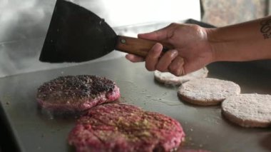 Spatulalı ekin aşçısı restoranda sıcak yüzeyde pişen lezzetli hamburger pirzolasına dönüşüyor.