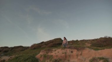 Yeşil tepede duran ve yazın akşamları doğaya hayran olan bir kadın gezgin.