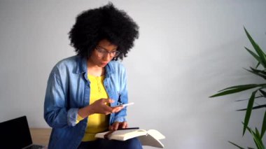 Siyah ekranlı dizüstü bilgisayarlı günlüğün fotoğrafını çekerken cep telefonu kullanan Afro-Amerikalı kadın.