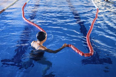 Plastik şerit ayırıcılarıyla havuzda yüzen tanınmamış kadın yüzücüden.