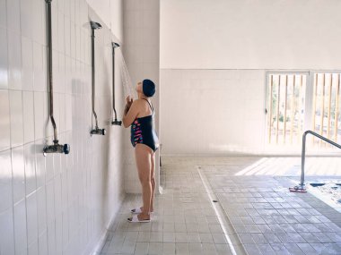 Su aerobiği eğitiminden önce havuzda duran mayolu olgun bir kadın.