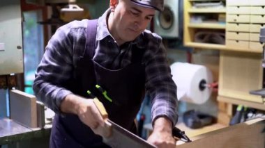 Marangoz, profesyonel atölyedeki tezgahta kereste keserken testere kullanıyor.