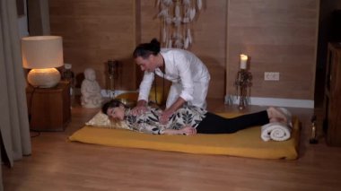 Beyazlı erkek pratisyenin yan görünüşü, kapalı gözlü bir kadının sırtını sıvazlıyor.