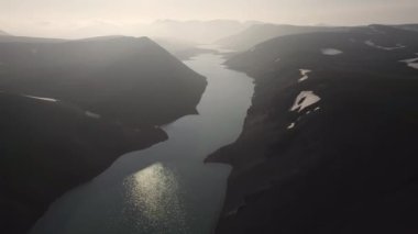 İzlanda 'da sabahın erken saatlerinde karla kaplı dağların arasında akan sakin nehir manzarası.