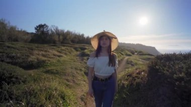 Güneşli bir günde yemyeşil çimenlikte yürürken güzel düşünceler içinde beyaz bluzlu, çekici, rüya gibi bir kadın.