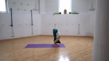 Spor kıyafetleri içinde kadın figürünün yarı yolda kaldırma ve alçak kaldırma hareketlerini gösterirken High Cobra pozları ile yoga yaparken odada poz verirken.