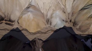 Yukarıdan baktığımızda, İzlanda 'da gündüz vakti dağların gölgesi altında, kum üzerinde akan dar kıvrımlı nehrin sağdan drone görüntüsü görüyoruz.