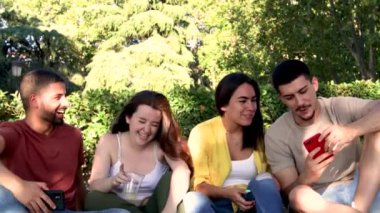 Bir grup arkadaş parkta çimlerde oturuyor. 