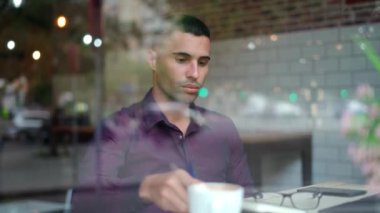Cam pencerelerden. Kafede kahve molası sırasında elinde bir bardak sıcak içecekle ciddi bir İspanyol erkek müdür.