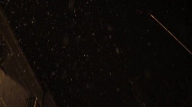 Eski duvarcılığın altından, karanlık gökyüzünün altında parlayan ışık ve alacakaranlıkta kar ile birlikte.