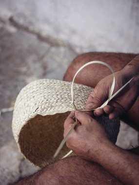 Avuç içi bantlı bir sepet dokuan bir zanaatkarın elleri, geleneksel zanaatkarlığı gösteriyor.