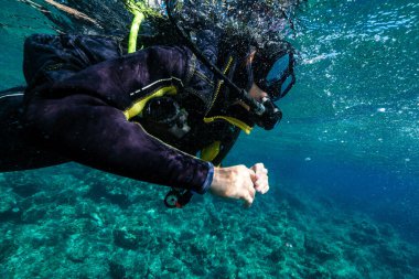 Siyah dalgıç kıyafetli ve maskeli tanınmayan aktif dalgıç, Menorca 'da tatilin tadını çıkarırken mercan resifinin yakınındaki derin okyanusta dalgıçlık yapıyor.