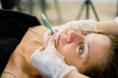 Bir estetik kliniğinde, hyaluronik asit, botoks ve tensör iplikleri de dahil olmak üzere yaşlanmayı önleyici bir prosedür uygulayan bir hastaya yakın çekim.