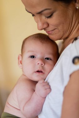 Ekin manzarası sakin genç bir kadının gündüz vakti tapılası bebeği kucaklaması ve okşaması.